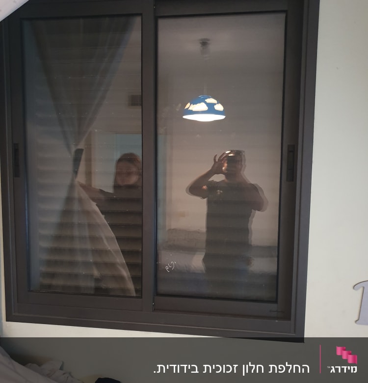 חלון זכוכית עם השתקפות אנשים ואור תלוי